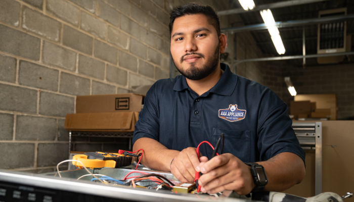 AAA Appliance technician at table working.