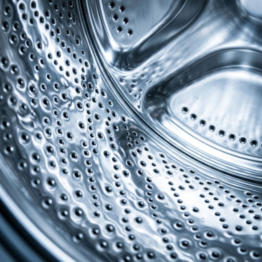A close-up view of a polished stainless steel washing machine drum interior.