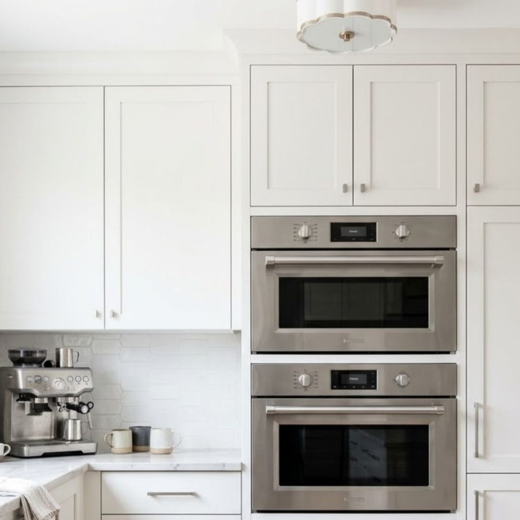 Built-in wall oven and microwave appliance stack in a modern white kitchen.